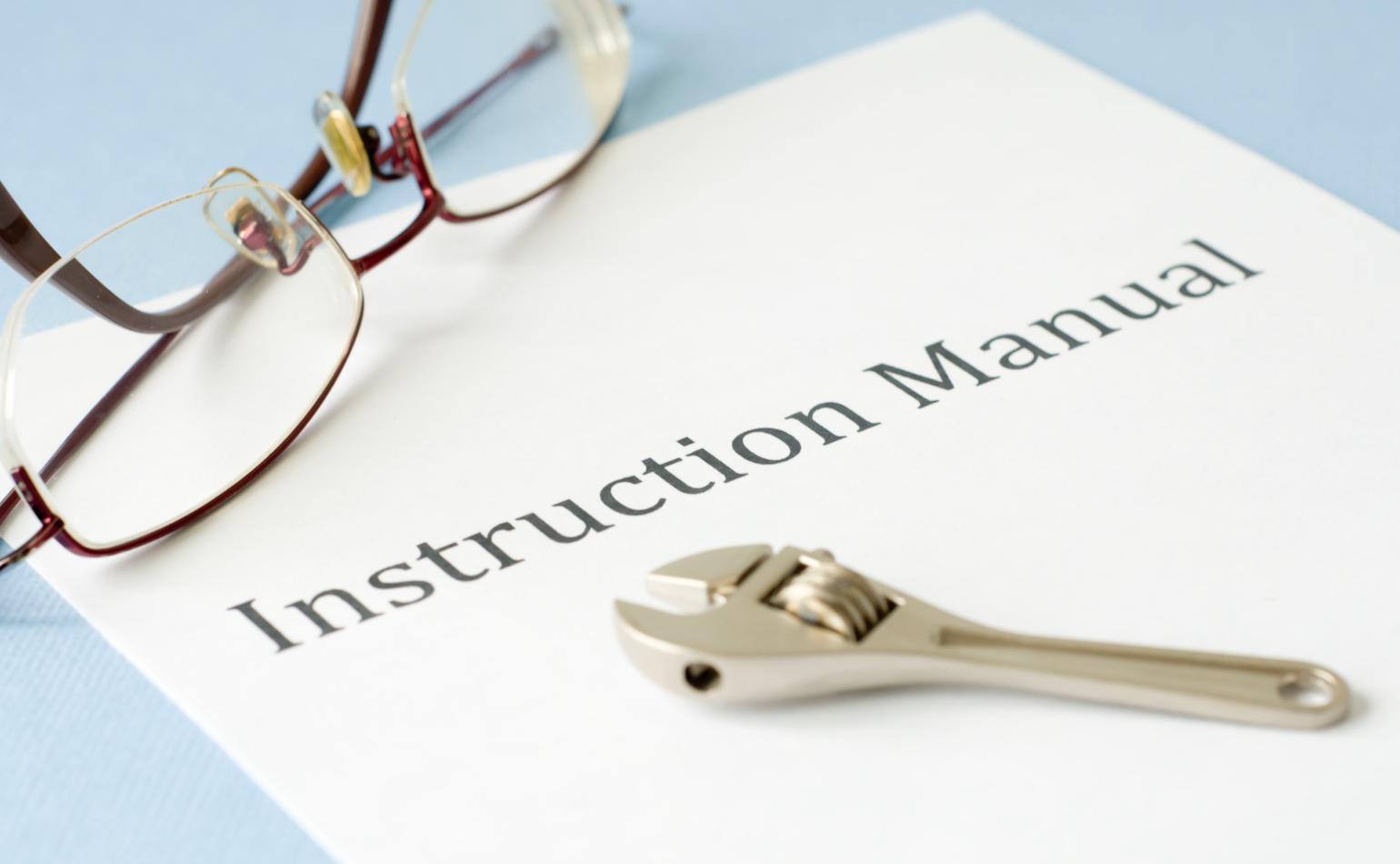An instruction manual with glasses and a wrench.