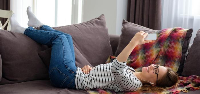 woman lying on couch with phone