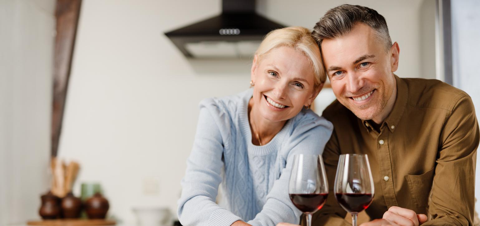 couple smiling looking at camera with glasses of wine