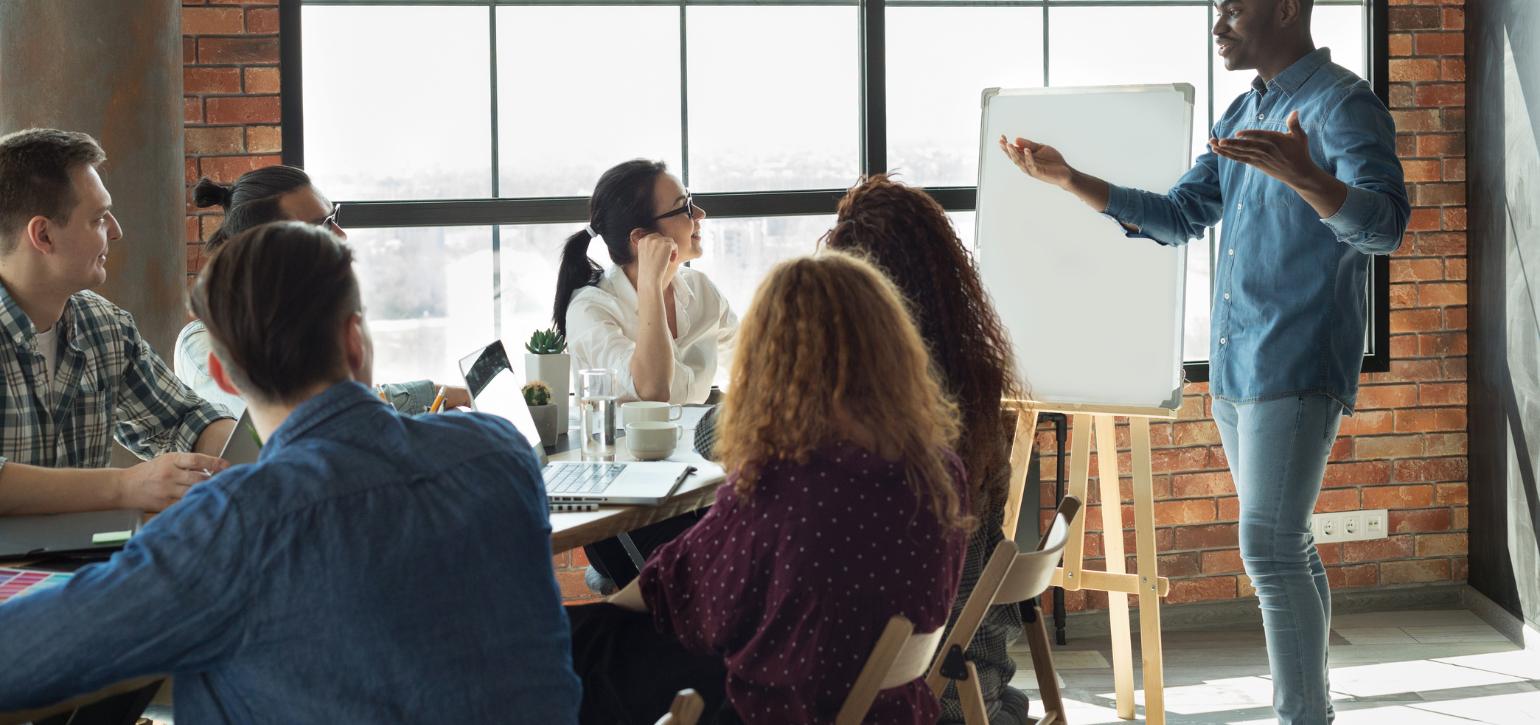 group of people in an office with an A frame presentation and speaker