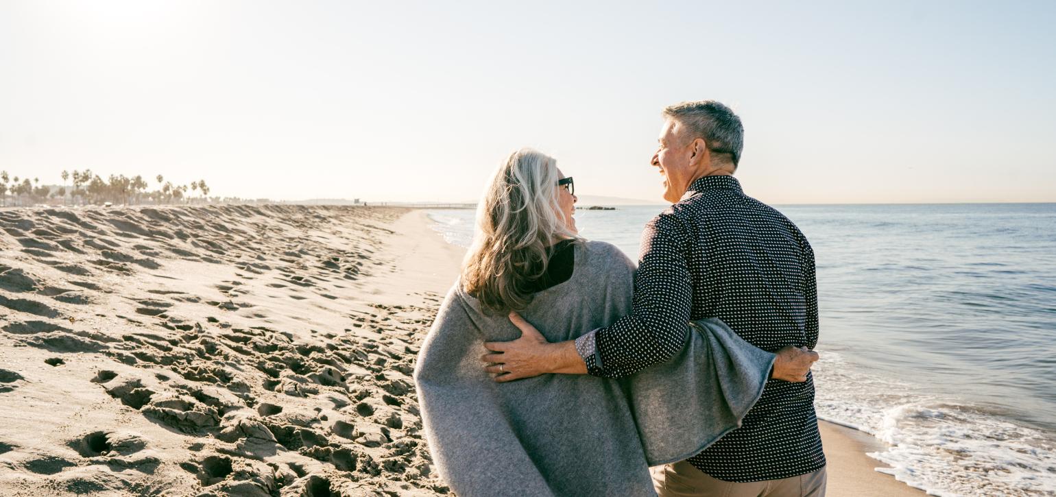 couple walking arm in arm on the beach