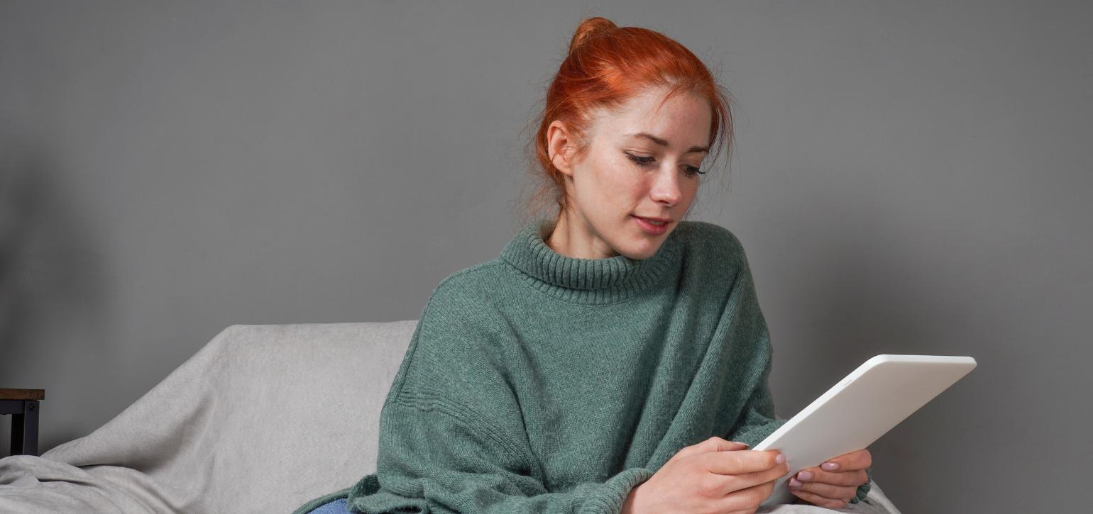 young woman sitting on chair looking at tablet