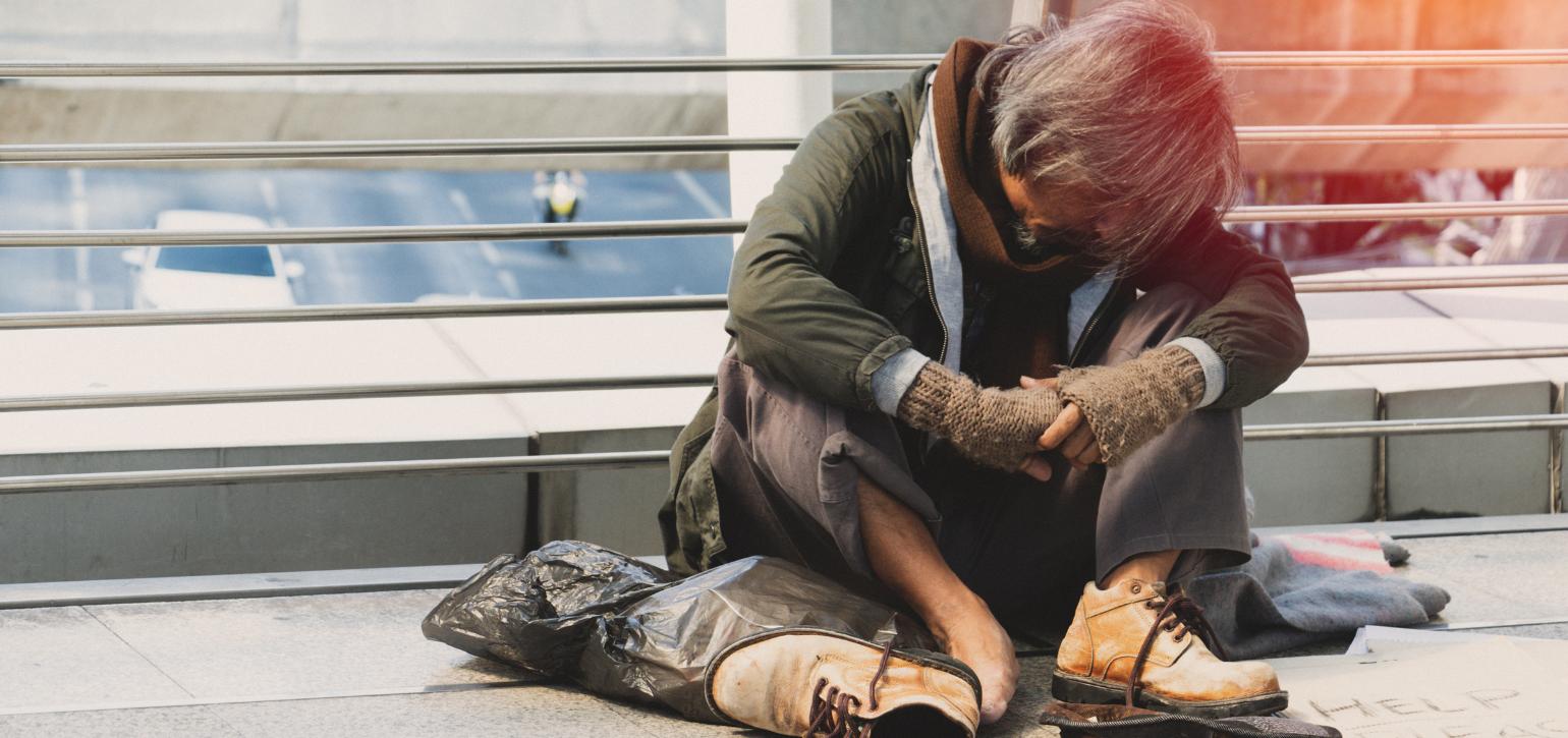 homeless person sitting with head down