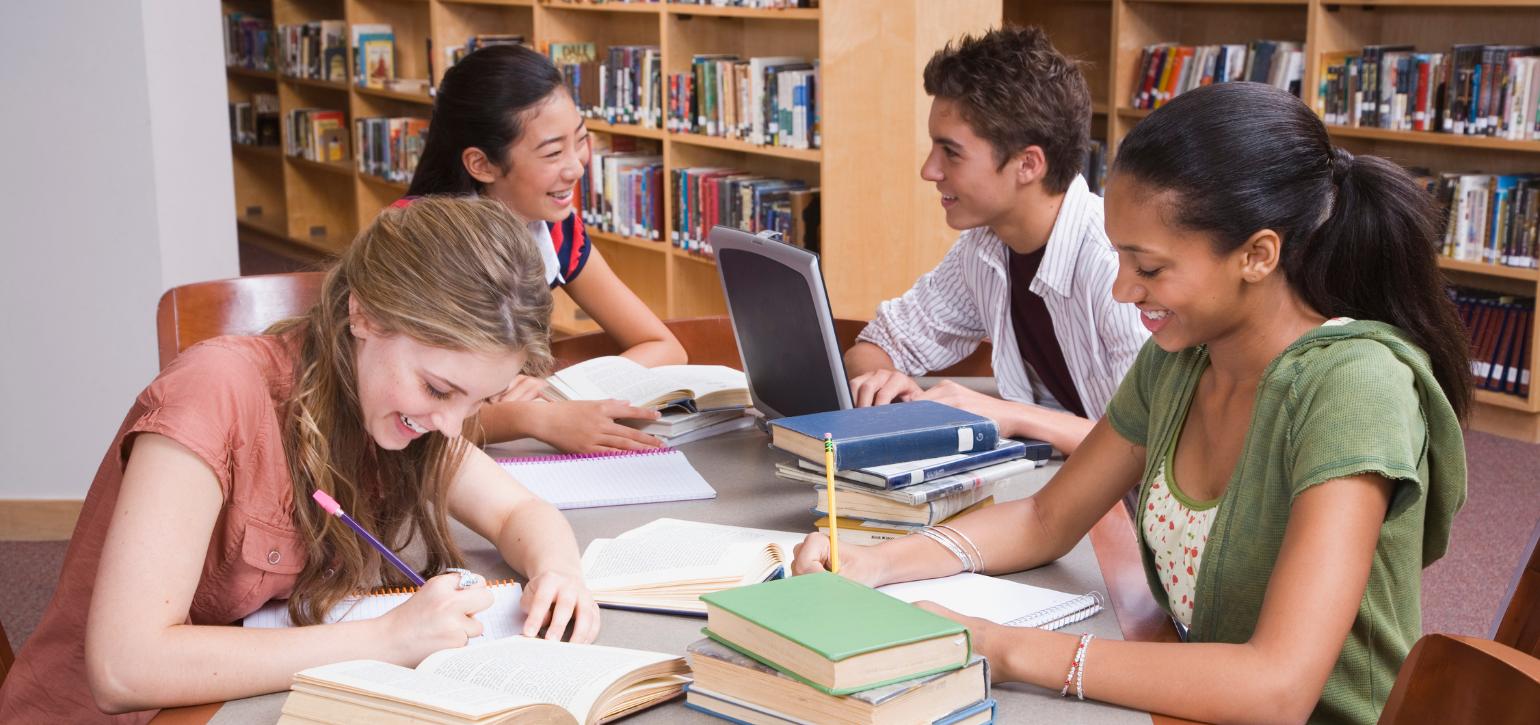 Teenagers in a library chatting and studying