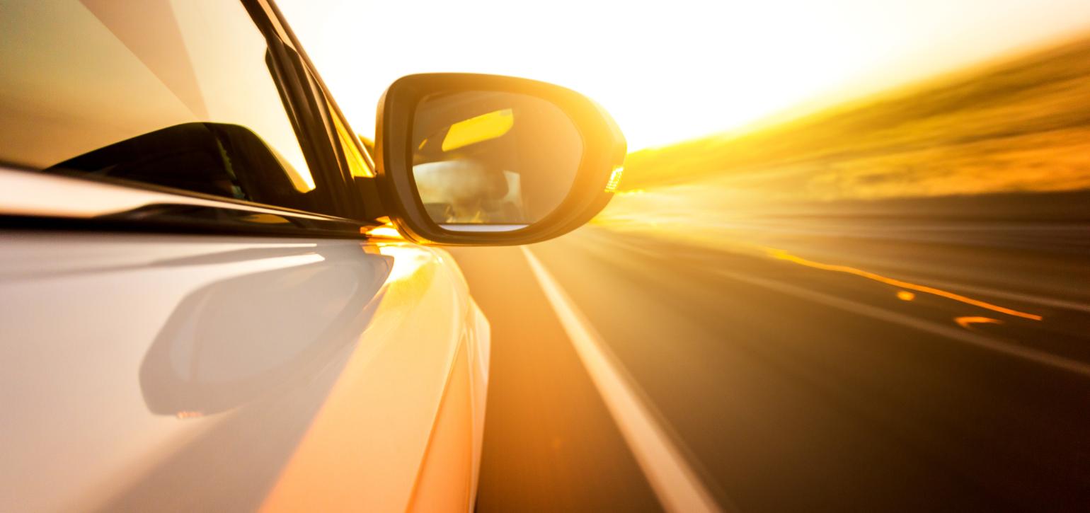 car driving into sunset