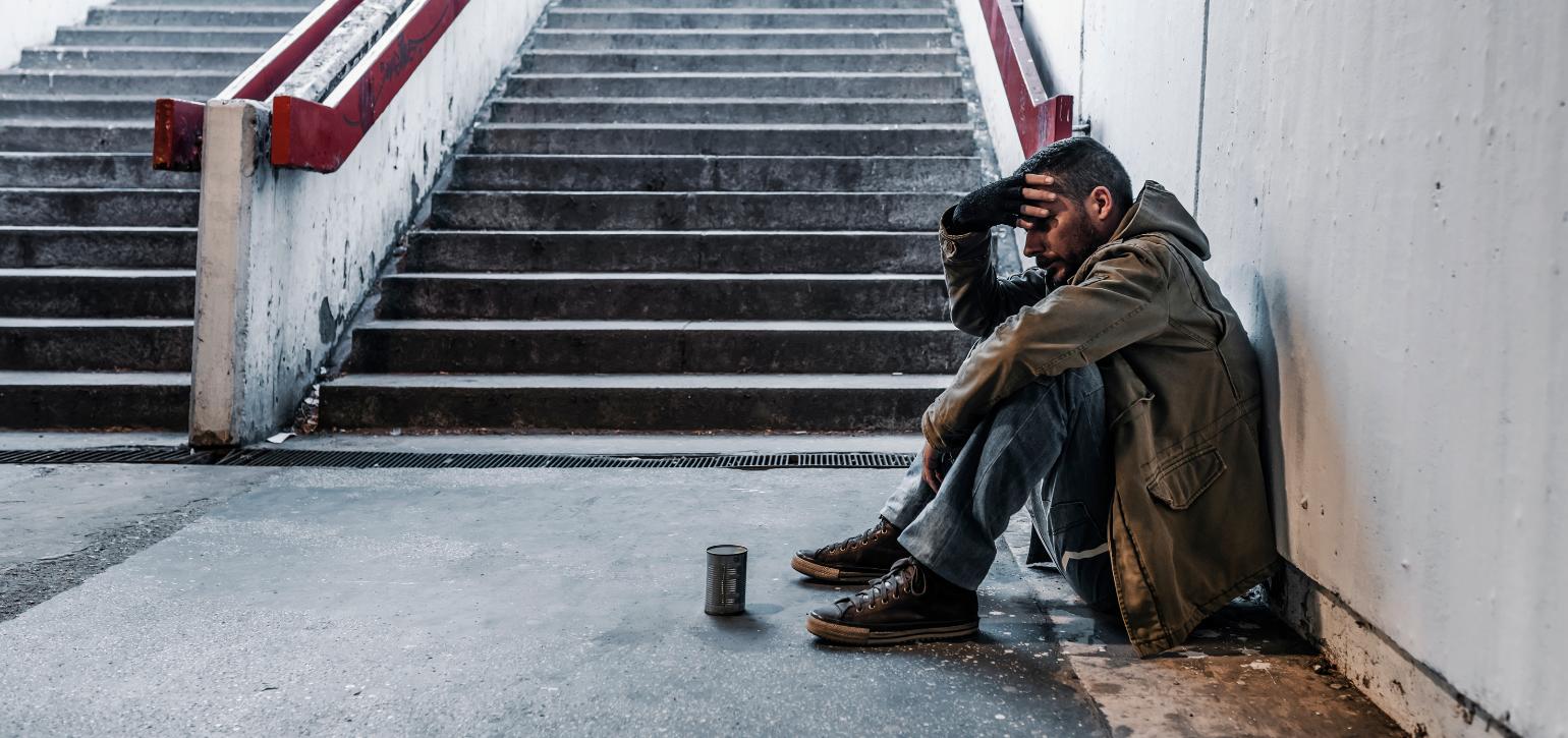 homeless man sitting at bottom of stairs