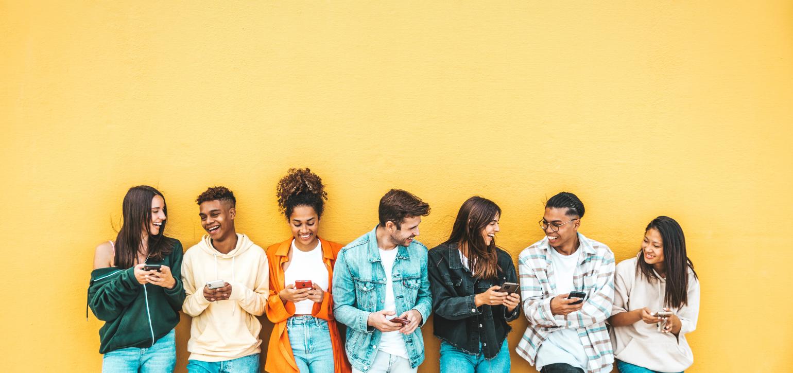 Young people standing against a yellow wall