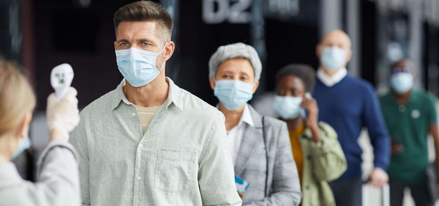 people in masks having temperature checked