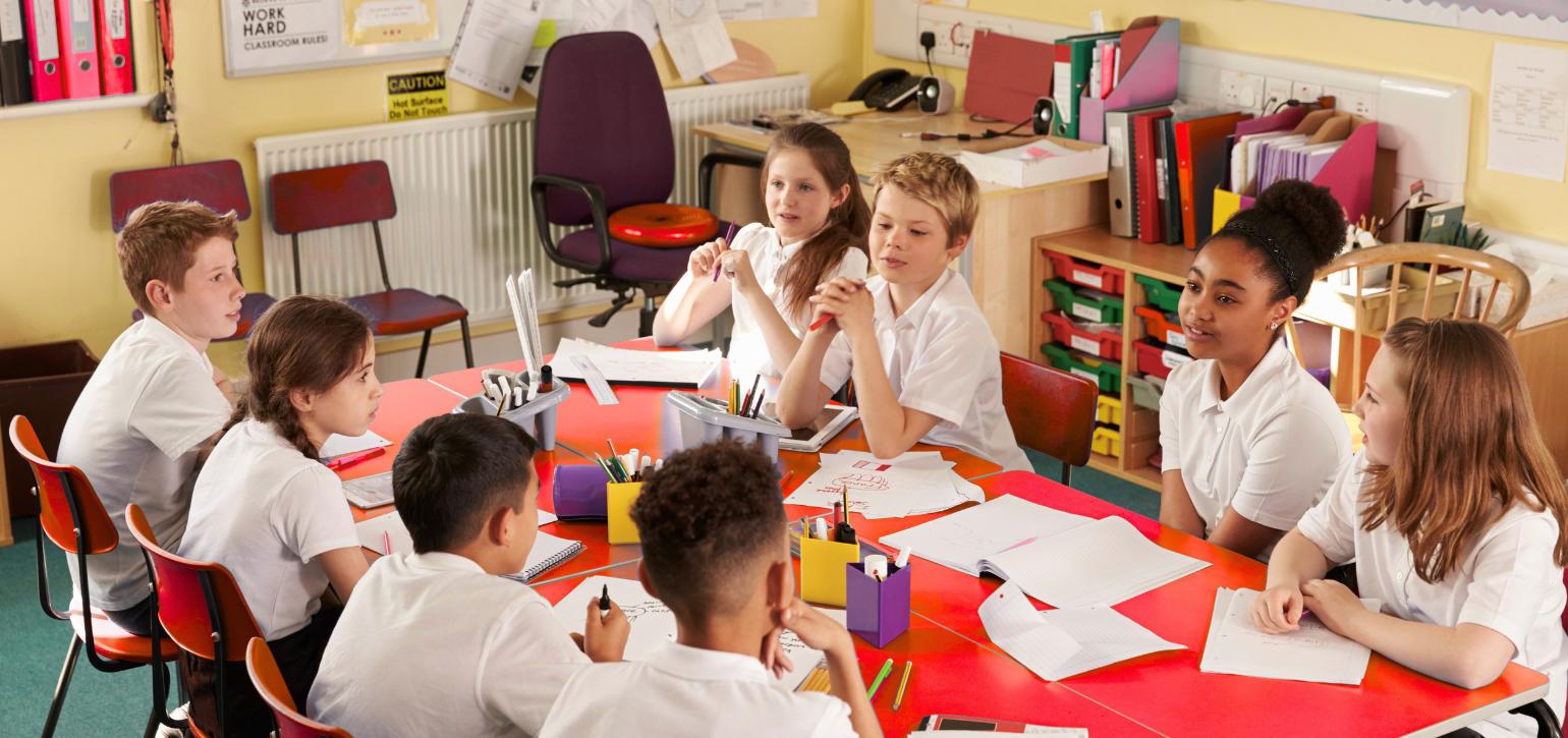school children sitting around a table in class