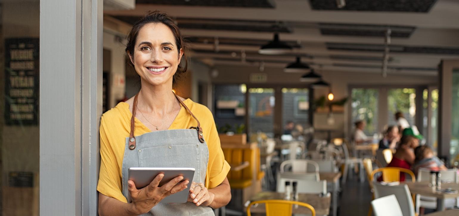 cafe owner standing outside business with tablet