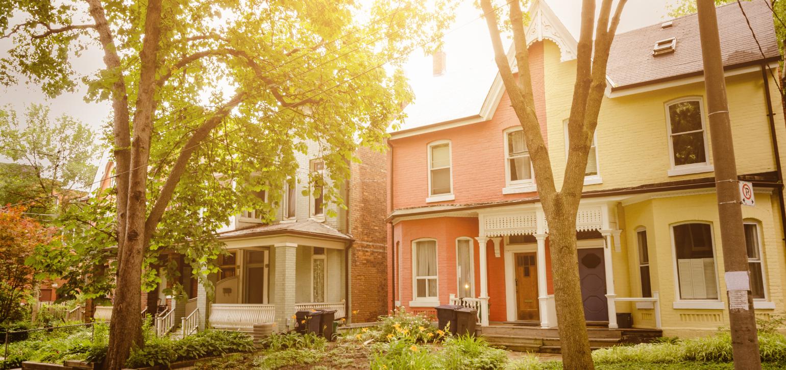 house on a suburban street with sun streaming through trees