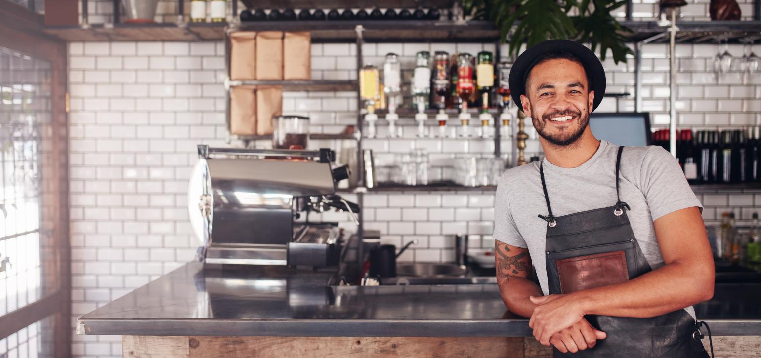 Barista leaning against a cafe counter