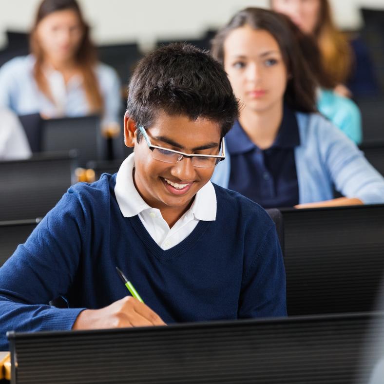 indian young boy in class smiling with students in background