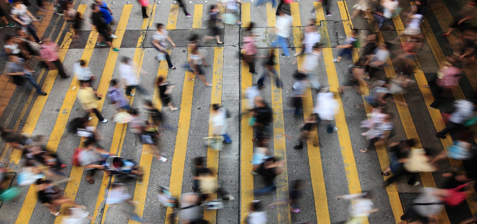 busy people rushing across a pedestrian crossing painted with yellow lines
