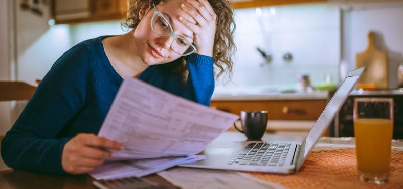 woman looking at bills with a laptop