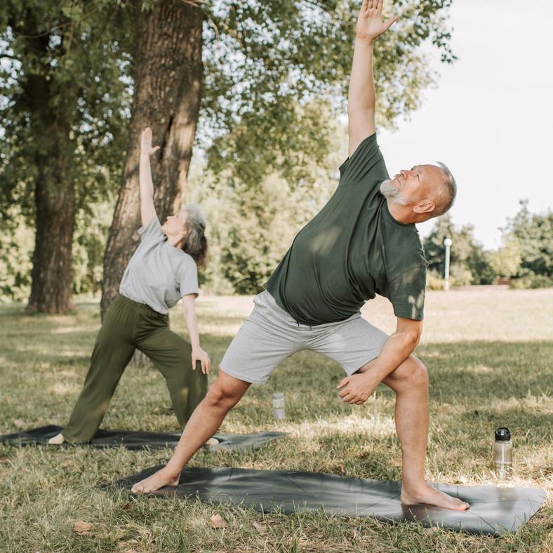 A retired couple do yoga in nature